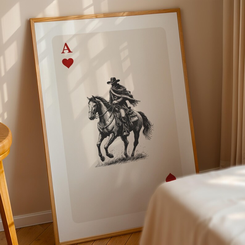 K&ouml;nnte beinhalten: Gerahmter Kunstdruck mit dem Pik-Ass. Das Kartendesign zeigt eine Schwarz-Wei&szlig;-Illustration eines Cowboys auf einem Pferd. Das Kunstwerk ist vor einem neutralen Hintergrund platziert, mit den roten Herzsymbolen und dem Buchstaben "A".