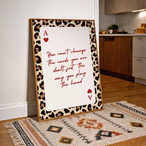 May include: A framed art print featuring a playing card design with a leopard print border. The card is an Ace of Hearts, with the text "You can't change the cards you are dealt, just the way you play the hand."
