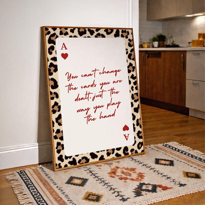 May include: A framed art print featuring a playing card design with a leopard print border. The card is an Ace of Hearts, with the text "You can't change the cards you are dealt, just the way you play the hand."