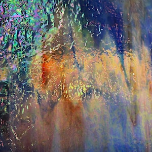 Op de afbeelding: Een plaat iriserend glas met een getextureerd, golvend oppervlak. Het glas vertoont een levendig kleurenspectrum, waaronder diepblauw, feloranje en glinsterend groen, wat een veelkleurig en lichtreflecterend effect creëert.