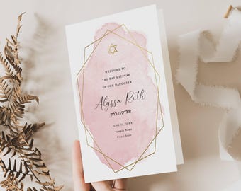May include: A white Bat Mitzvah invitation card featuring a pink watercolour wash background enclosed in a gold geometric frame. The text reads Welcome to the Bat Mitzvah of our daughter Alyssa Ruth, with Hebrew text, a Star of David, and date details.