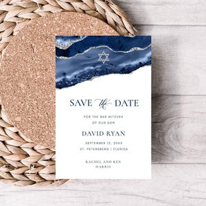 May include: A navy blue and white "Save the Date" card with a Star of David and abstract blue design. The card includes the text "Save the Date" and details for a Bar Mitzvah, including the son's name, date, and location.