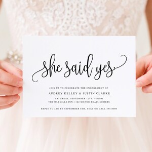 May include: White invitation card with the text "She said yes" in elegant black script. The card announces the engagement of Audrey Kelley & Justin Clarke, with event details including date, time, and location.