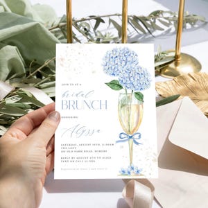 This beautiful design features delicate blue hydrangea flowers, in a gold champagne glass, perfect for your bridal shower or brunch celebration.