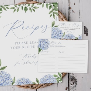 May include: A white recipe card set featuring blue hydrangea illustrations and green leaves. The large sign reads Recipes, Please leave your recipe here, Thanks for sharing. The small card reads Share a Recipe, Please bring your favorite recipe to share.
