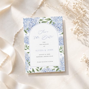 May include: A rectangular wedding save the date card featuring a white arched center panel with blue text reading Save the Date for the wedding of Alyssa & John, August 10, 20XX, Newport, Rhode Island, surrounded by watercolor blue hydrangea flowers.