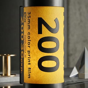 May include: A cylindrical lamp designed to resemble a 35mm color print film canister. The lamp features a yellow and black design with the number "200" prominently displayed. The text "35mm color print film" is also visible. The lamp is a unique decorative item.