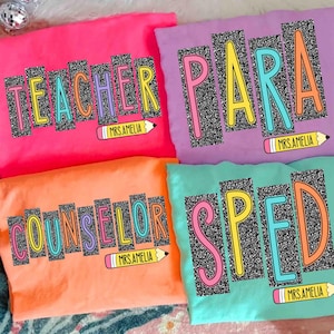 May include: Four brightly colored t-shirts with teacher-themed designs. Each shirt features a different word: "TEACHER", "PARA", "COUNSELOR", and "SPED", in a colorful, outlined font with a glittery black background. Each shirt also has a pencil graphic and the text "MRS.AMELIA".