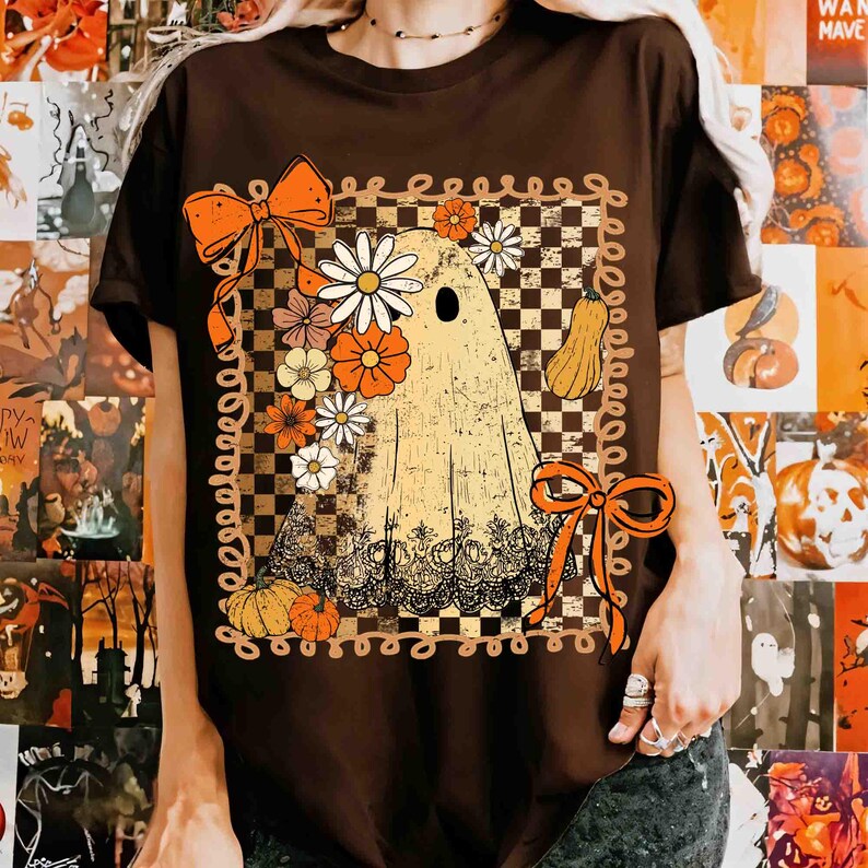 Puede incluir: Camiseta marr&oacute;n con un dise&ntilde;o de fantasma retro adornado con flores, calabazas y lazos. El fantasma tiene una corona floral y est&aacute; sobre un fondo a cuadros. El dise&ntilde;o utiliza tonos naranja, blanco y amarillo.