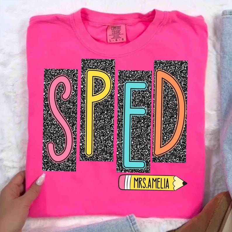 May include: A hot pink t-shirt with the word "SPED" in colorful block letters. The letters are set against a black and white speckled background. A yellow pencil with the text "MRS.AMELIA" is at the bottom.