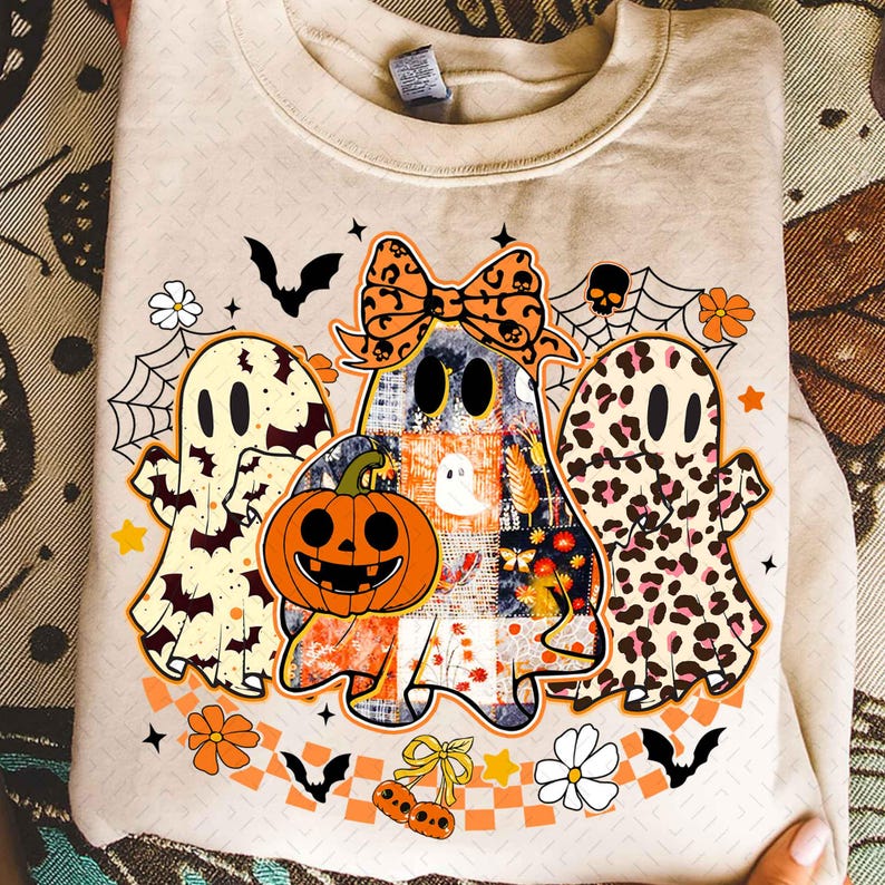 Peut inclure: Sweat-shirt beige avec un motif d'Halloween. Le motif comprend trois fant&ocirc;mes de dessins anim&eacute;s, une citrouille, des chauves-souris, des fleurs et un n&oelig;ud. Les fant&ocirc;mes ont diff&eacute;rents motifs, dont le patchwork et l'imprim&eacute; l&eacute;opard.