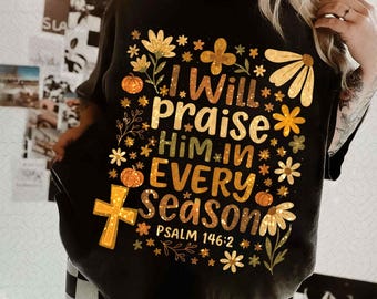 May include: Black t-shirt with the text "I Will Praise Him in Every Season" and Psalm 146:2. The design includes floral and pumpkin graphics in yellow, orange, and brown. The shirt is a casual style.