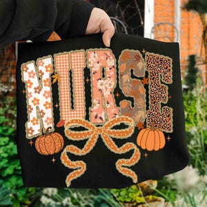 Könnte beinhalten: Schwarze Tragetasche mit dem Wort "NURSE" in einem Herbst-Design. Die Buchstaben weisen florale, karierte und Leopardenmuster auf. Eine große orangefarbene Schleife und zwei Kürbisse sind ebenfalls enthalten.
