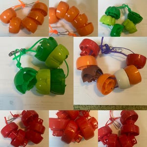 May include: A selection of brightly coloured plastic components, including orange, green, and red pieces, linked together with strings and clasps. The objects seem to be parts of a larger item or decorative elements. The image displays a variety of shapes and colours.