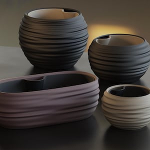 May include: A collection of four planters featuring a horizontal ribbed texture. Two are spherical and dark gray, one is a smaller spherical planter in light beige, and one is an elongated oval planter in a muted mauve tone with a dark gray interior.