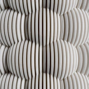 May include: A white object featuring a repeating pattern of stacked, vertical, circular discs that create a textured, spherical, and layered surface. The bottom right corner displays the text st3rn. in a small, black, sans-serif font.