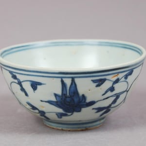 Peut inclure: Un bol en céramique blanc avec un motif floral bleu. Le bol a une forme arrondie avec un bord légèrement évasé. Le motif bleu présente une fleur centrale et des vignes. Le bol mesure environ 15 cm de diamètre.