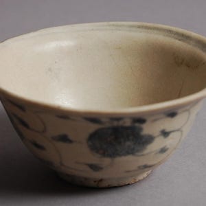 Peut inclure: Un bol en céramique blanche avec un motif floral bleu et blanc. Le bol est rond et a un bord légèrement évasé.