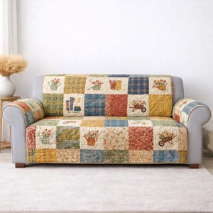 Puede incluir: Una funda de sofá patchwork con temática de jardín. La funda presenta cuadrados de varios patrones y colores, incluyendo estampados florales, cuadros y tonos lisos. Imágenes bordadas de regaderas, flores y carretillas se distribuyen por la funda.