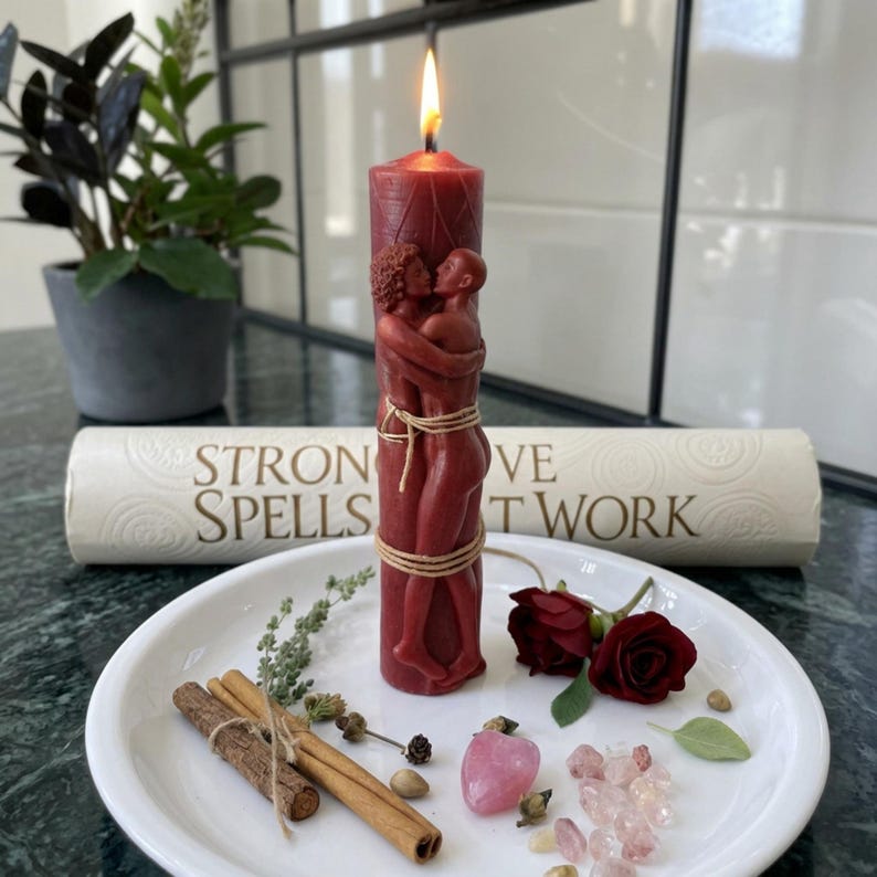 May include: A lit, burgundy-colored candle with a carved design of embracing figures, tied with twine. The candle sits on a white plate with cinnamon sticks, rose buds, and crystals. A rolled scroll behind the candle reads "STRONG SPELLS LOVE THAT WORK."