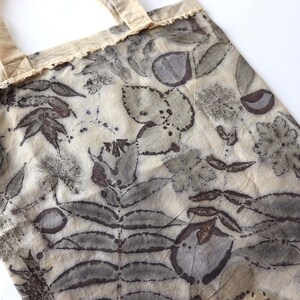 Puede incluir: Una bolsa de tela beige con un ribete de encaje y un estampado bot&aacute;nico en tonos marrones y grises.