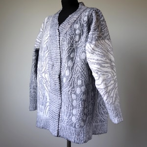 May include: A gray and white patterned cardigan with a V-neck and long sleeves.