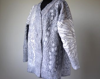 Peut inclure: Un cardigan gris et blanc à motifs avec un col en V et des manches longues.