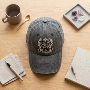 May include: A white ceramic mug with a black handle and the text "But First, Coffee" in a black, handwritten-style font. The mug is on a white surface.