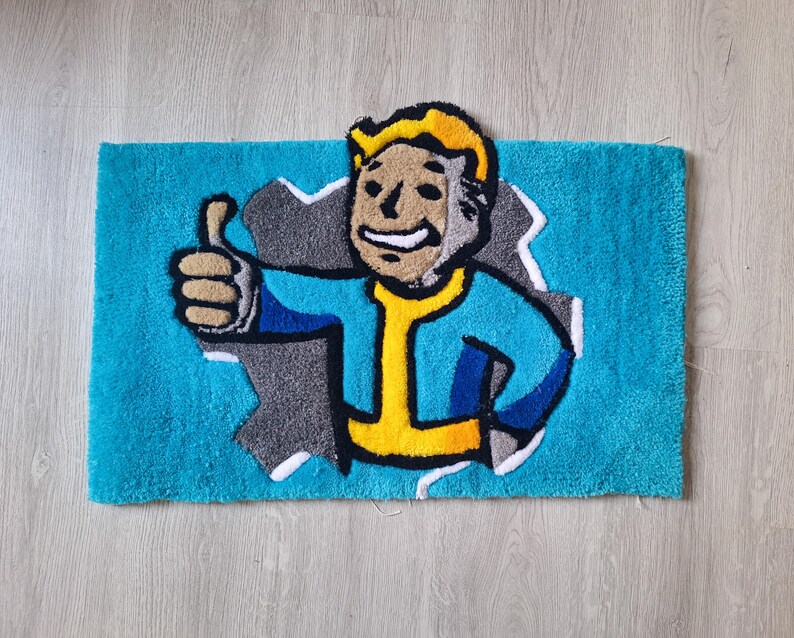 May include: A blue bath mat with a cartoon character of a man with yellow hair and a blue jumpsuit. The man is giving a thumbs up and is partially sticking out of a hole in the mat.