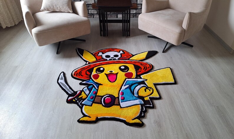 K&ouml;nnte beinhalten: Ein individuell geformter Teppich mit dem gelben Charakter Pikachu, der einen roten Piratenhut mit wei&szlig;em Totenkopf-Emblem, eine blaue Jacke und einen braunen G&uuml;rtel tr&auml;gt und ein silbernes Schwert in der rechten Hand h&auml;lt.
