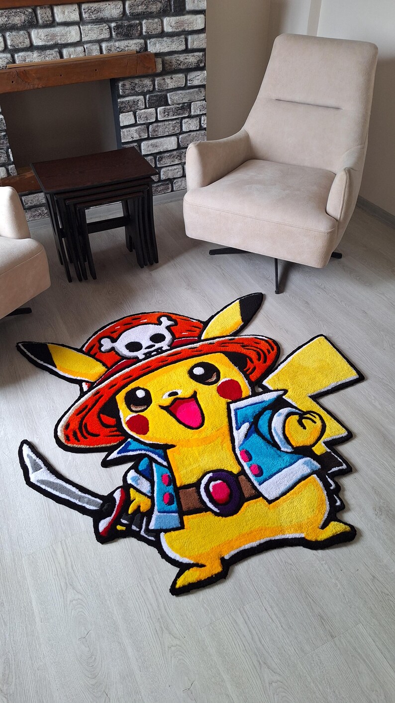 K&ouml;nnte beinhalten: Ein getufteter Teppich in Form der Figur Pikachu, die einen roten Piratenhut mit wei&szlig;em Totenkopf-Emblem, eine blaue Jacke und einen braunen G&uuml;rtel tr&auml;gt und ein silbernes Schwert mit schwarzem Griff und roten Akzenten auf dem Boden h&auml;lt.