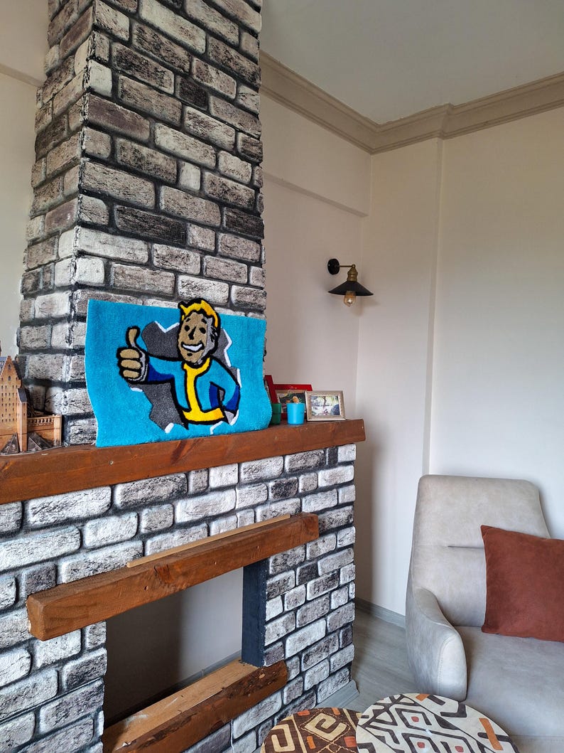 May include: A brick fireplace with a wooden mantel and a blue rug with a cartoon character on it. The rug has the text "Vault-Tec" on it. There is a small armchair with a brown pillow in the corner of the room.