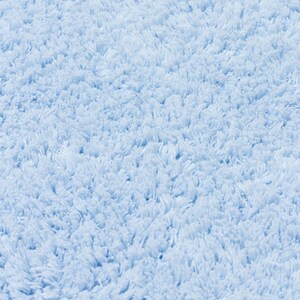 May include: Close-up of a light blue fluffy bath mat. The texture is soft and plush.