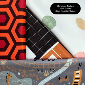 May include: Three fabric swatches with different patterns. The first is a red and black geometric pattern. The second is a black and white grid pattern with a brown and orange geometric pattern on top. The third is a white fabric with green, brown, and pink watercolor dots. The text "Gorgeous Texture Vivid Colors Stain Resistant Fabric" is printed on the third swatch.
