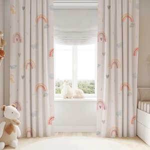 May include: A pair of white curtains with a rainbow and heart pattern. The curtains are hung in a nursery with a white crib and a stuffed animal.