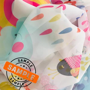May include: A white sheer fabric with a colorful print of birds, flowers, and raindrops. The fabric has a sample label with the word "SAMPLE" printed on it.