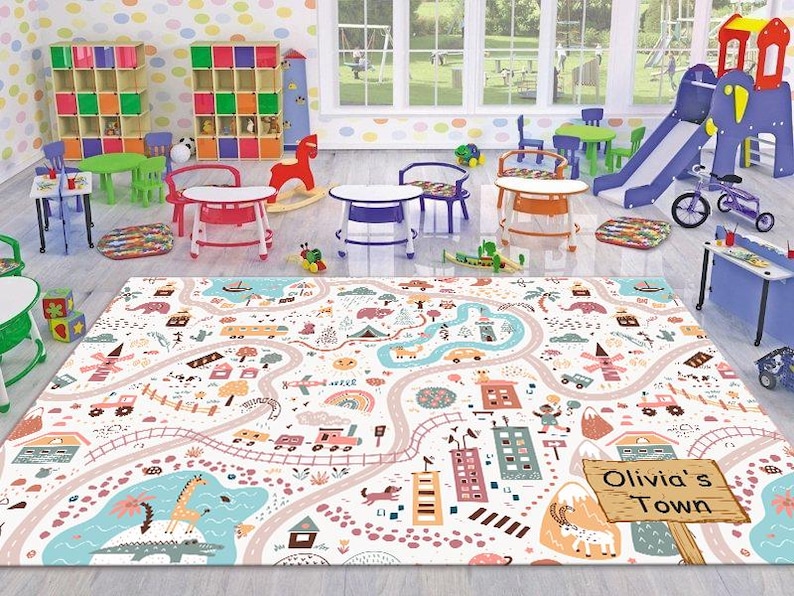 May include: A colorful play mat with a town theme, featuring a winding road, buildings, and a sign that reads "Olivia's Town".