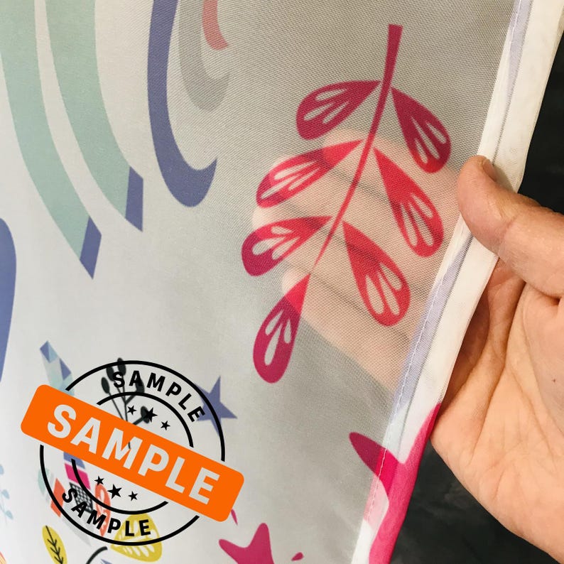 May include: A white sheer fabric with a colorful pattern of rainbows, stars, and leaves. The fabric has a white border and the word "SAMPLE" is printed in orange on a black circle.
