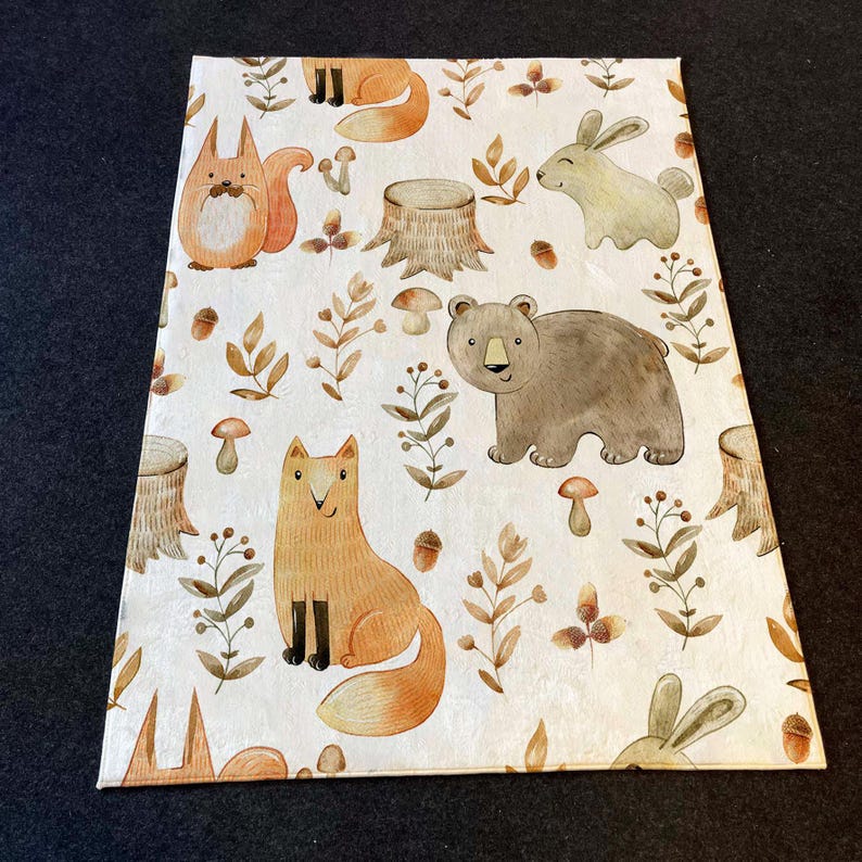 May include: A white rug with a woodland animal print. The rug features foxes, bears, rabbits, and tree stumps. The animals are drawn in a cartoon style with watercolor-like details.