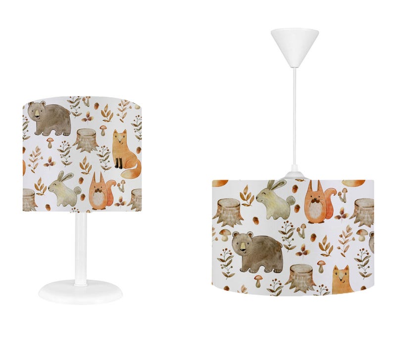 May include: Two white lampshades with a woodland animal print. The lampshades feature a brown bear, a fox, a squirrel, and a rabbit. The print is in watercolor style and has a light brown background.