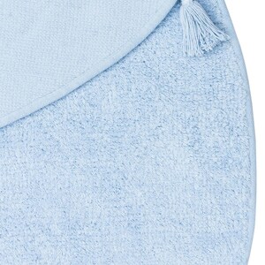 May include: A light blue round bath mat with a tassel on the edge.