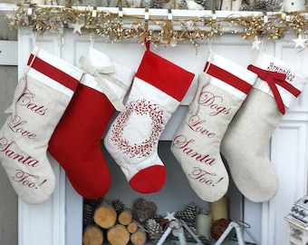 May include: Four Christmas stockings hanging on a white fireplace mantel. The stockings are made of white fabric with red trim and are embroidered with the words "Cats Love Santa Too!" and "Dogs Love Santa Too!" One stocking has a red bow and the text "Brandilee".