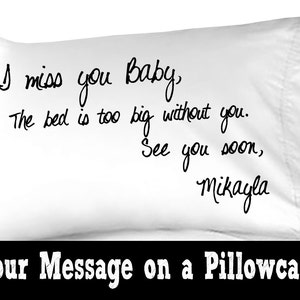 May include: White pillowcase with black handwritten text that reads "I miss you Baby, The bed is too big without you. See you soon, Mikayla".