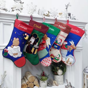 May include: Five personalized Christmas stockings with embroidered names: Luna, Dad, Mom, Matt, and Nicole. Each stocking features a different festive design, including a bear, Santa Claus, an angel, a gnome, and a reindeer.