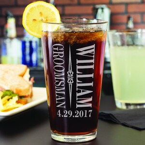 May include: A clear glass beer stein with the text "William Groomman 4.29.2017" etched on the side. The stein is filled with a dark brown liquid.