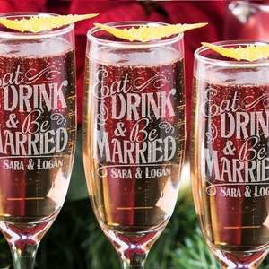 Puede incluir: Tres copas de champ&aacute;n con el texto "Eat Drink & Be Married" y los nombres "Sara & Logan" grabados en la parte delantera.