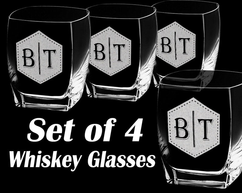 Puede incluir: Juego de cuatro vasos de whisky con base cuadrada y forma &uacute;nica. Cada vaso presenta un hex&aacute;gono blanco con las iniciales "BT" en una fuente serif. El texto "Set of 4 Whiskey Glasses" se muestra debajo.