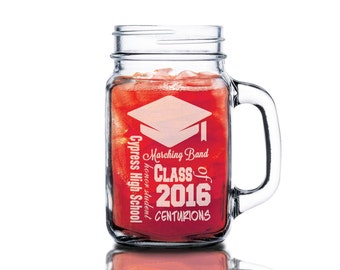 May include: A clear glass mason jar mug with a red liquid inside. The jar has a white design that says "Cypress High School honor student Marching Band Class of 2016 Centurions".