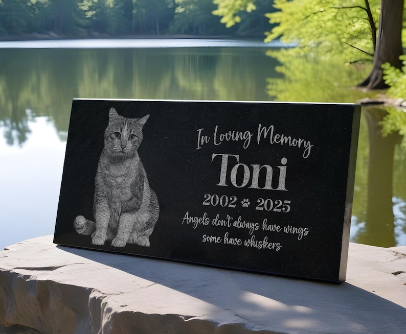 May include: Black granite pet memorial with a photo of a cat and the inscription "In Loving Memory Toni 2002-2025 Angels don't always have wings some have whiskers"