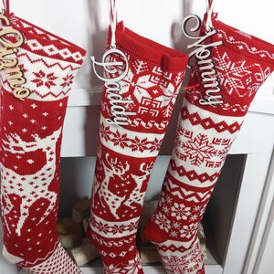 May include: Three red and white knitted Christmas stockings with wooden name tags that say "Mommy", "Daddy", and "Olivia".